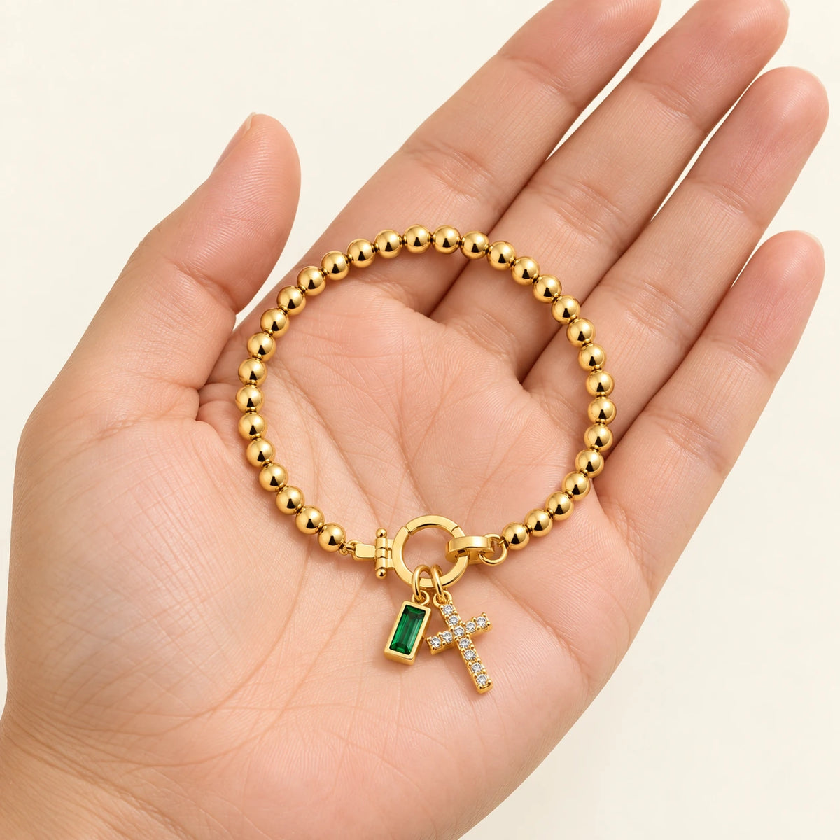 Birth Month Crystal Cross Charm Bracelet held in hand, showing its true scale
