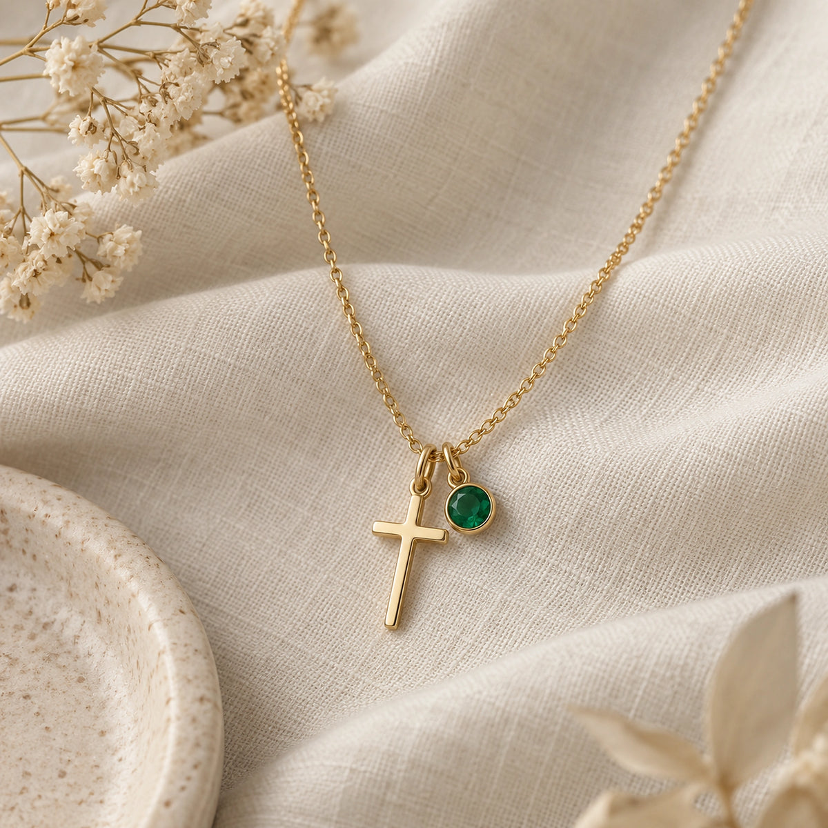 Birthstone Cross Necklace laid on ivory linen.