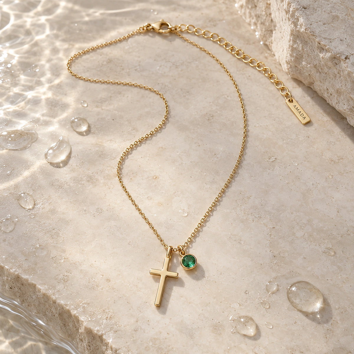 Birthstone Cross Necklace with water droplets on a light surface.