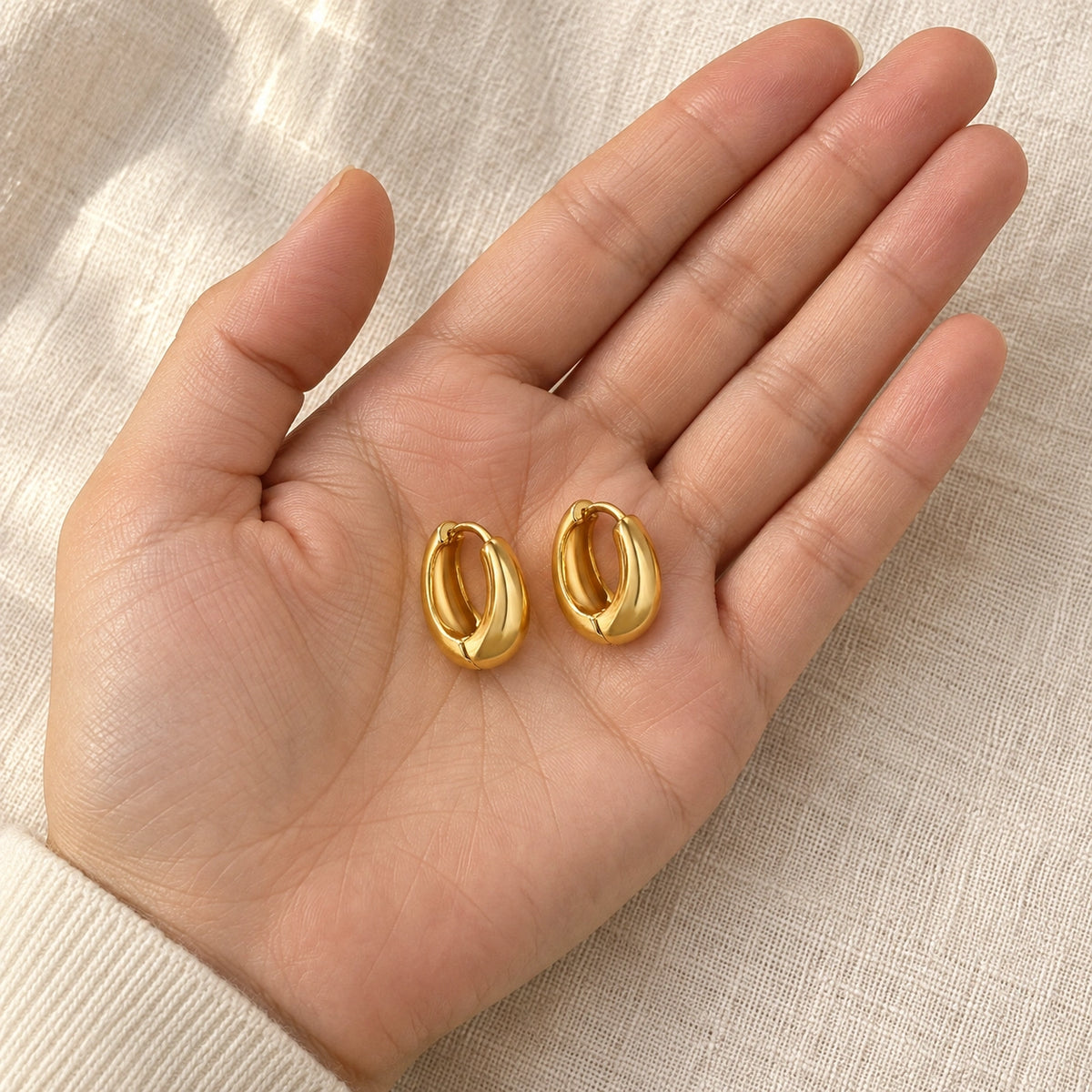 Amada Chunky Hoop Earrings held in a hand for a sense of its real size.