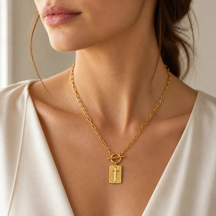 Gold-plated cross pendant worn at the neckline