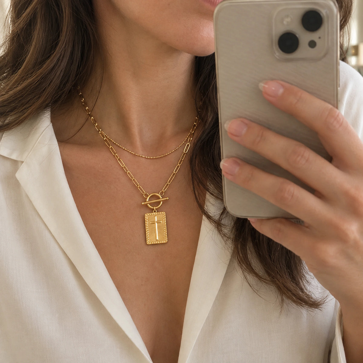 Amada Nail Cross Necklace layered with a delicate gold chain and styled with an ivory blouse.