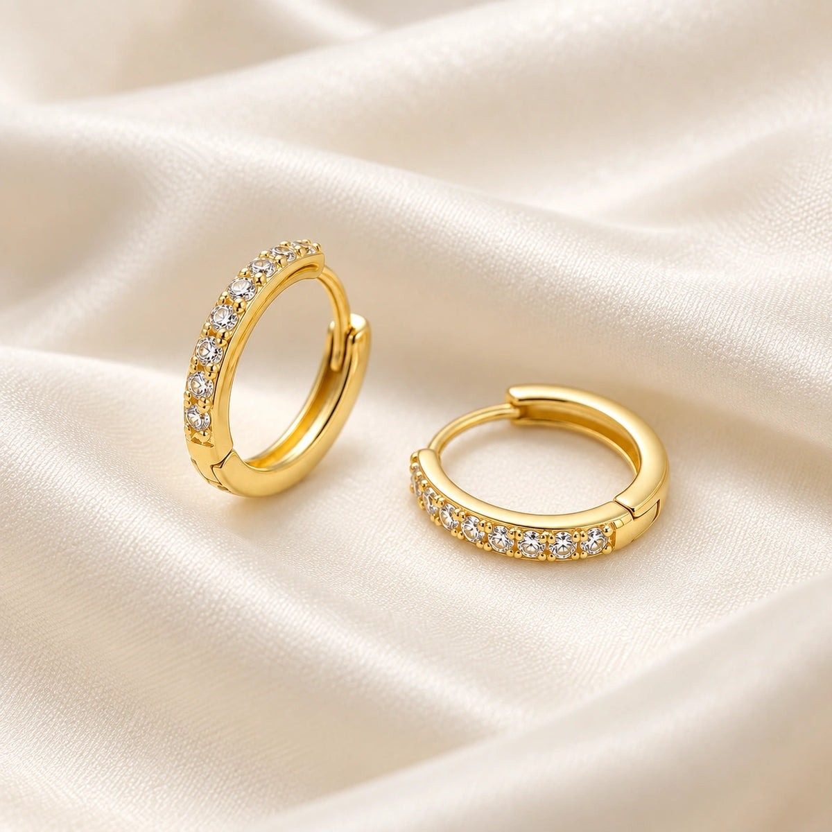 Amada Pave Huggie Earrings laid flat on fabric.