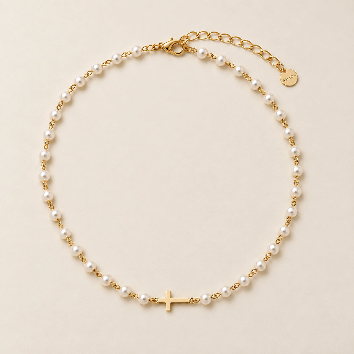 Amada Pearl Cross of Grace Necklace with pearls, gold links and an integrated cross, on an ivory background.