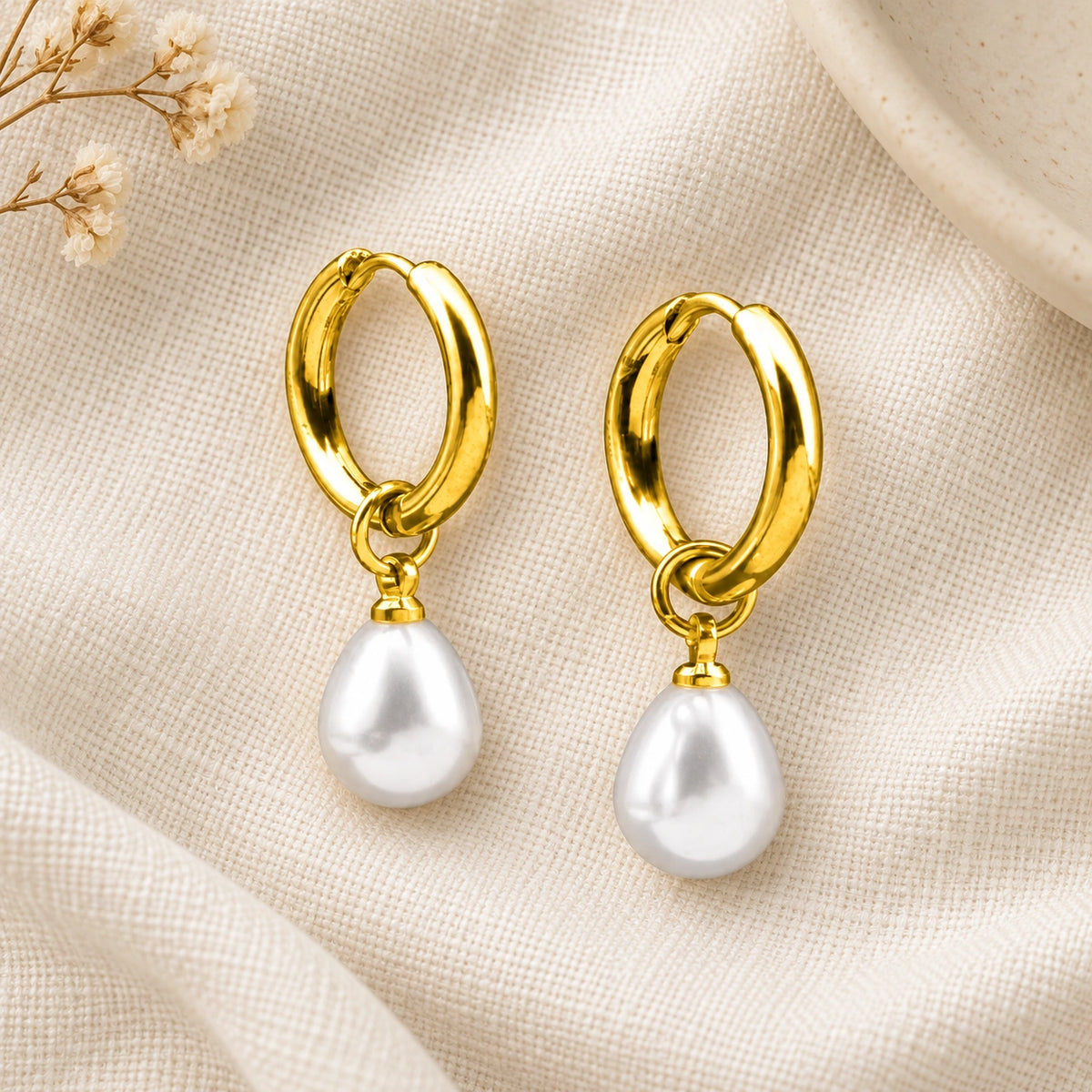 Amada Petite Faux Pearl Huggie Earrings laid flat on fabric.