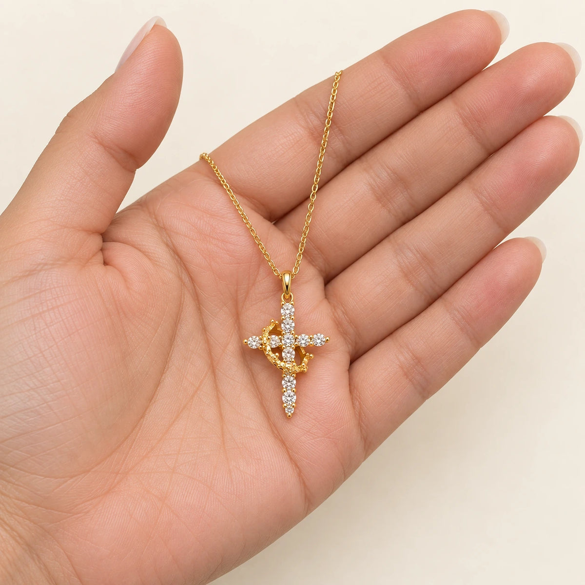 Rotating Crown Cross Necklace held in hand, showing its true scale