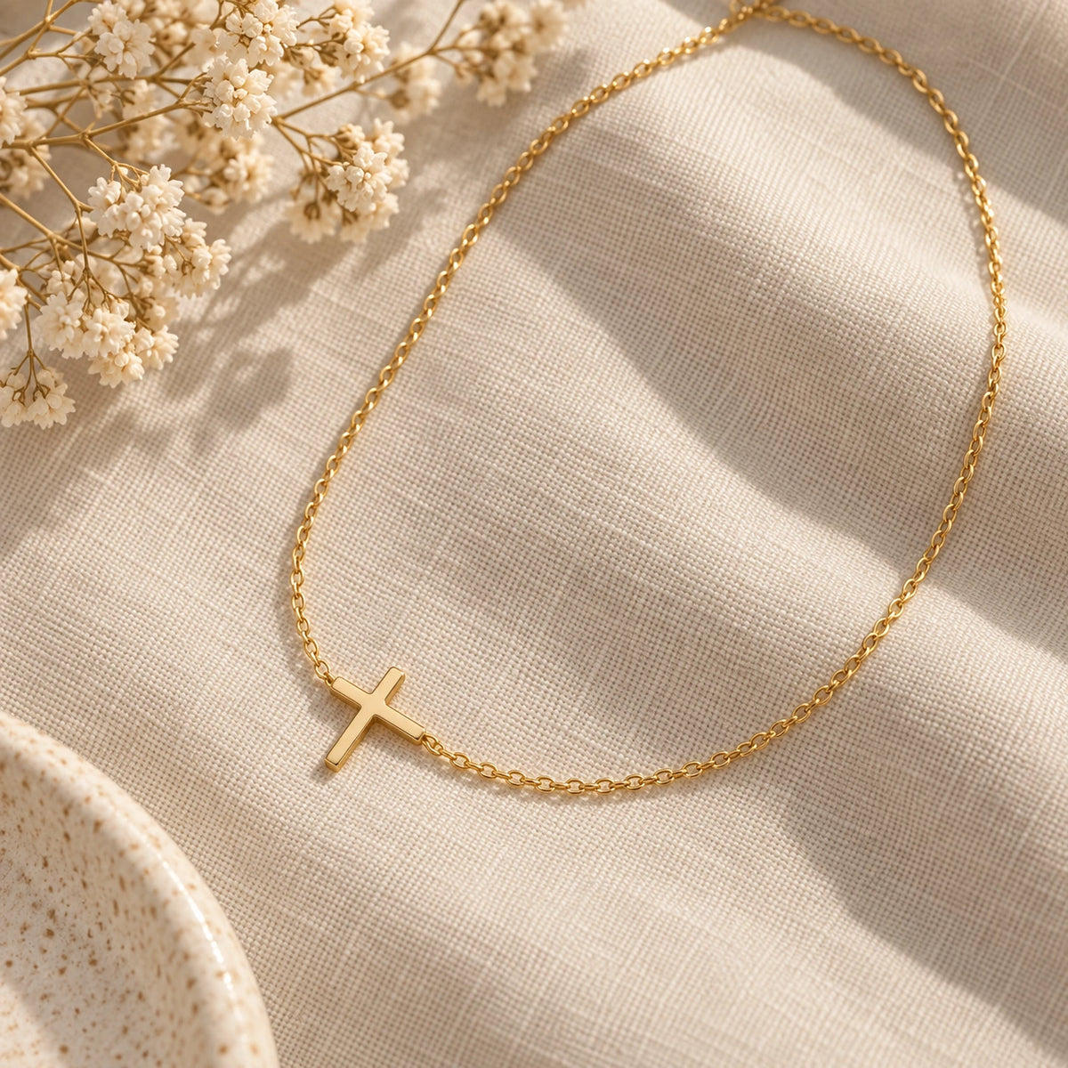 The Classic Cross Necklace laid flat on linen