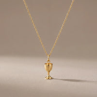 Chalice, a sealed 18K gold chalice pendant necklace, on a plain background