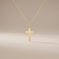 Guardian Cross, a sealed 18K gold cross pendant necklace, on a plain background