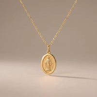 Our Lady Watches, a sealed 18K gold Our Lady medal necklace, on a plain background