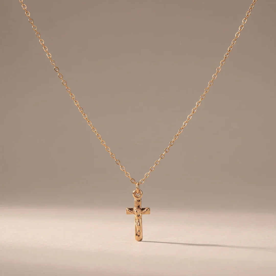 The Vow, a sealed 18K gold crucifix necklace, on a plain background